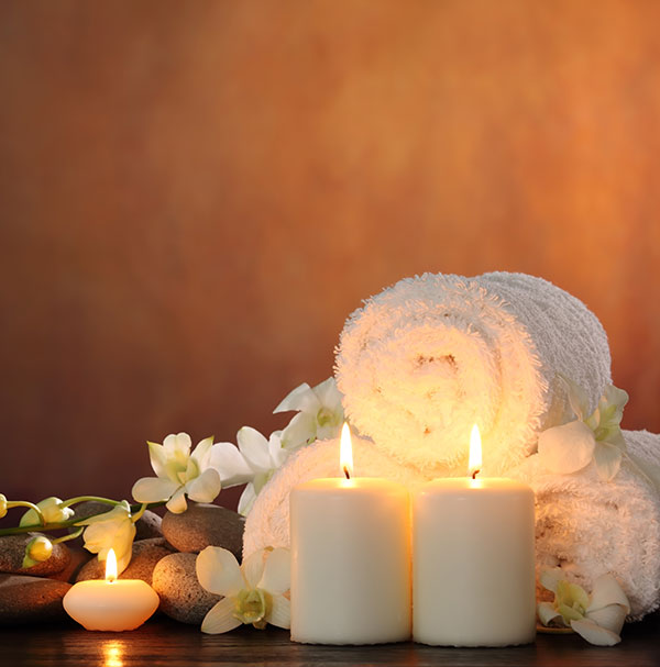 lit candles in front of towels, rocks and flowers