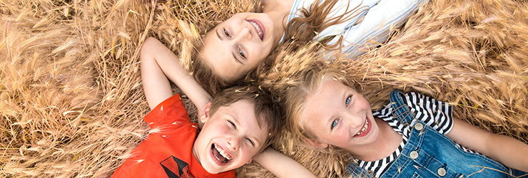 three kids smiling and laying on the ground