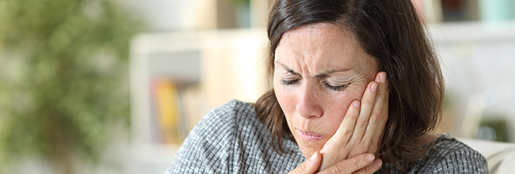 Woman in pain holding her jaw where her temporomandibular joint is