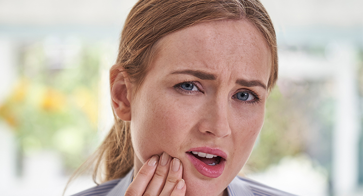 Woman with tooth pain holding her jaw in a dental emergency