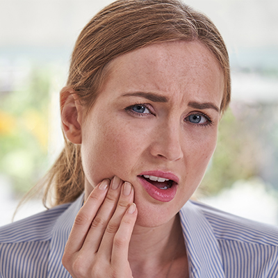 Woman with tooth pain holding her jaw in a dental emergency